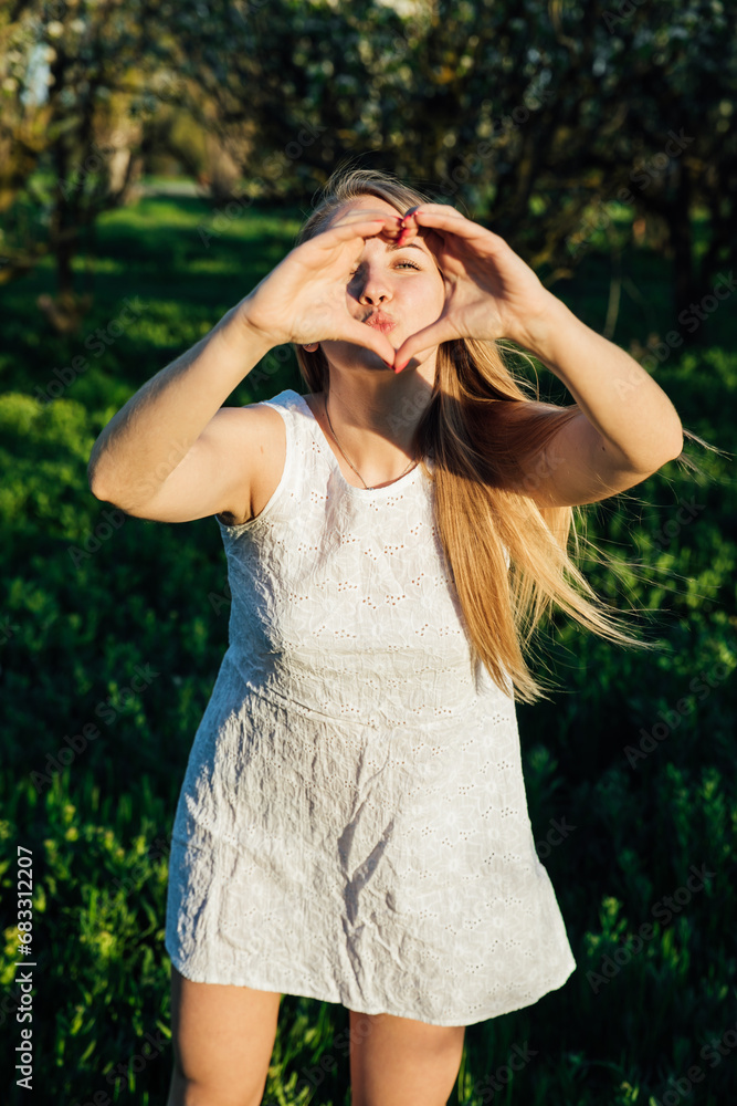 Beautiful woman shows heart in park walk nature