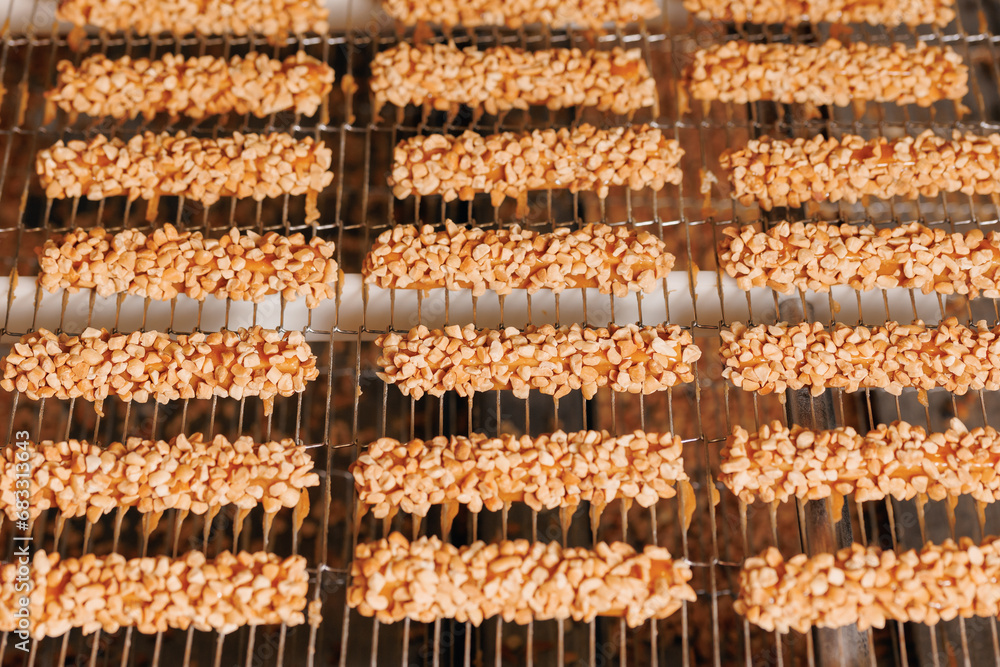 Waffles with nuts are coated with chocolate on conveyor. Food industry Production line of modern sweet candy bakery factory