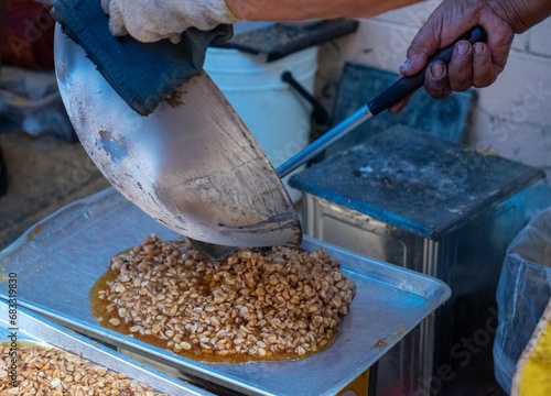 Chef Pouring Well Done of Peanut in Caramelized Syrup on a Tray 