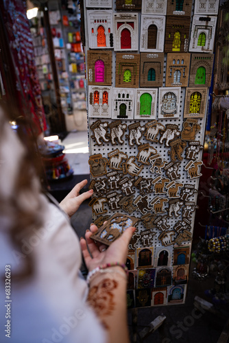 Obraz na płótnie (Selective focus) Defocused girl in the foreground choosing a magnet in Marrakesh's souk, Morocco. The souks of Marrakech are the largest in Morocco and famous globally. w salonie
