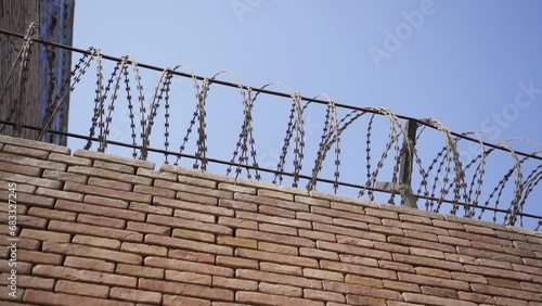 A brick wall with a security wire fence. A jail wall from above. Outdoor. Prison yard. Freedom, war, forbidden, crime, protection, dangerous, control, escape concepts. (ID: 683327245)