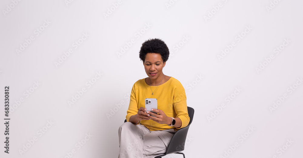 Confident young businesswoman messaging over smartphone while sitting on chair over white background Confident young businesswoman messaging over smartphone while sitting on chair over white background