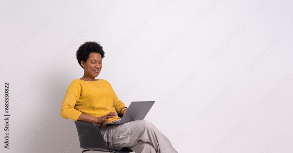 Female professional analyzing sales report over laptop while sitting on chair over white background Female professional analyzing sales report over laptop while sitting on chair over white background