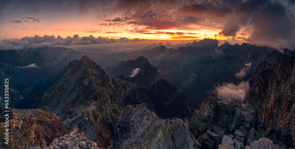 Sunrise at Rysy peak in Tatra Mountains with rocky foreground. Colofrul sky with clouds in early morning. Slovaki and Poland border at the top.