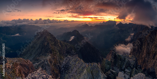 Sunrise at Rysy peak in Tatra Mountains with rocky foreground. Colofrul sky with clouds in early morning. Slovaki and Poland border at the top.