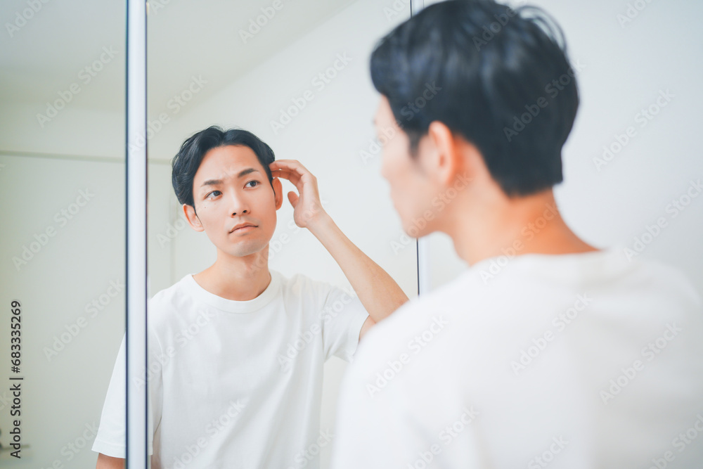 Obraz premium 洗面所でヘアセットをする男性