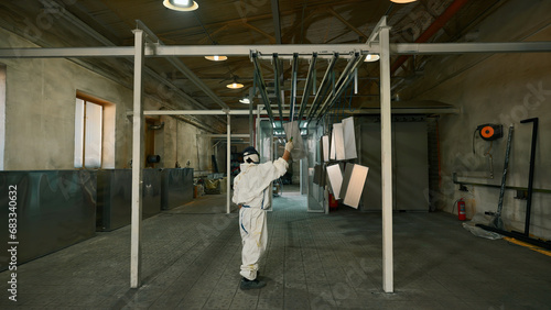 Tableau sur toile Worker pushing line of painted metal sheets into the drying chamber