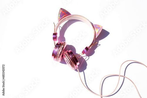 Beautiful pink headphones with cat ears on a white background. Contrasting shadows on a sunny day. Flat lay