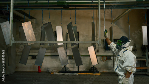 Fotografie Worker pushing line of painted metal sheets into the drying chamber