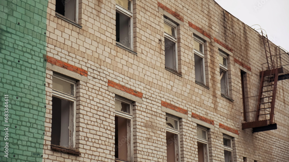 Obraz premium Old abandoned brick building used for housing and rental apartments or hospital. Clip. Broken windows of a ruined house.