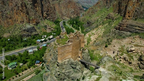 Erzurum Enguzek Castle is in ruins by the river and has been waiting for centuries Mountains clouds in the sky photo