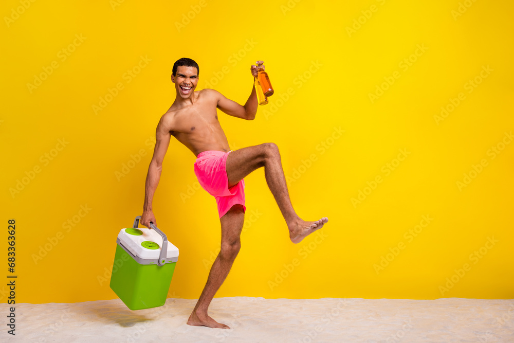 Full length photo of funny excited shirtless man holding refrigerator inviting drink beer empty space isolated yellow color background - obrazy, fototapety, plakaty 