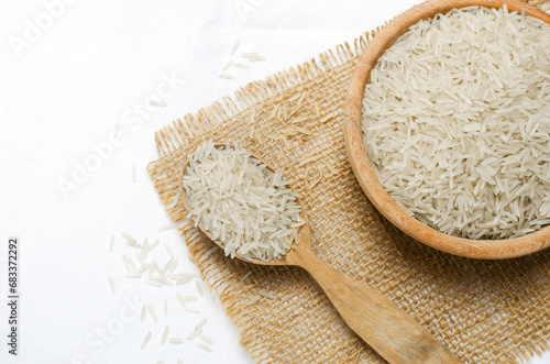 Raw basmati rice in wooden spoon and bowl on burlap. Concept of Water-Conserving Products. Saving water. Horizontal orientation. Top view. Copy space.