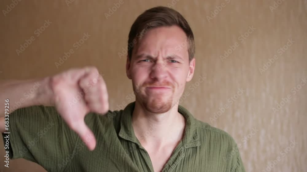Portrait of dissatisfied man showing thumbs down gesture. Annoyed man expressing dislike indoor Portrait of dissatisfied man showing thumbs down gesture. Annoyed man expressing dislike indoor