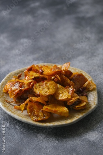 Spicy chips potato on dak background. Traditional food with rustic plate. Kering kentang photo