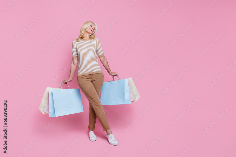 Full length photo of adorable woman dressed trendy clothes looking empty space poster isolated on pink color background Full length photo of adorable woman dressed trendy clothes looking empty space poster isolated on pink color background