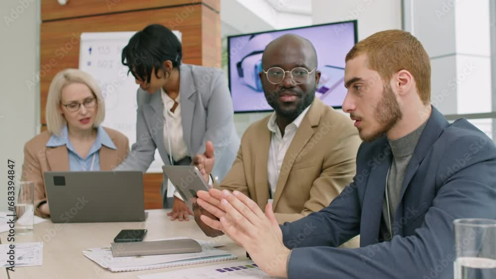 Selective focus on two male corporate colleagues sitting in conference room full of people brainstorming ideas Selective focus on two male corporate colleagues sitting in conference room full of people brainstorming ideas