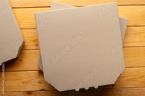 Pizza closed carton box on natural wooden table flat lay mockup with copy-space