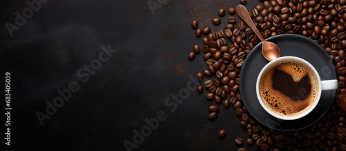 Top down view of delicious espresso in a cup surrounded by coffee beans and spoon Dark background with banner