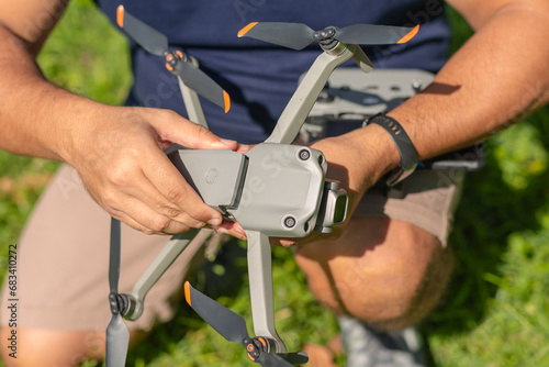 A man attaches a fresh and fully-charged battery onto a consumer level drone prior to a flight. photo