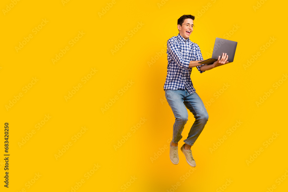 Photo of excited guy wear shirt spectacles jumping high typing modern device isolated vibrant color background