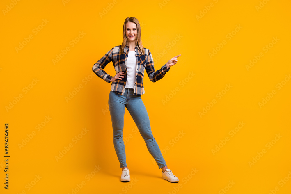Attractive smiling young woman finger idicating new product sale presentation isolated over yellow studio wall Attractive smiling young woman finger idicating new product sale presentation isolated over yellow studio wall