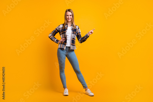 Attractive smiling young woman finger idicating new product sale presentation isolated over yellow studio wall