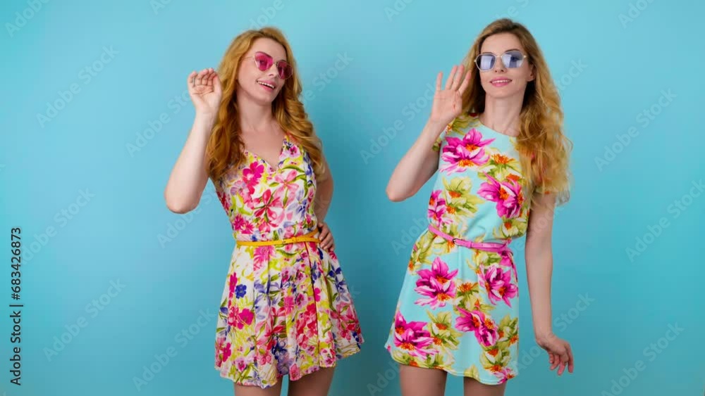 Friends, woman showing handshake gesture, hello hi, smiling friendly, invite. Two women sister exited greeting and welcoming, wave hand in trendy outfit, friendly laughing. Studio blue background. Friends, woman showing handshake gesture, hello hi, smiling friendly, invite. Two women sister exited greeting and welcoming, wave hand in trendy outfit, friendly laughing. Studio blue background.