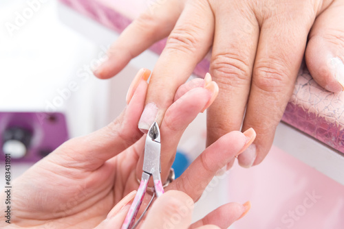 Close-up of a woman in a nail salon, a beautician cuts her cuticles, Woman getting a manicure in a spa center. 
