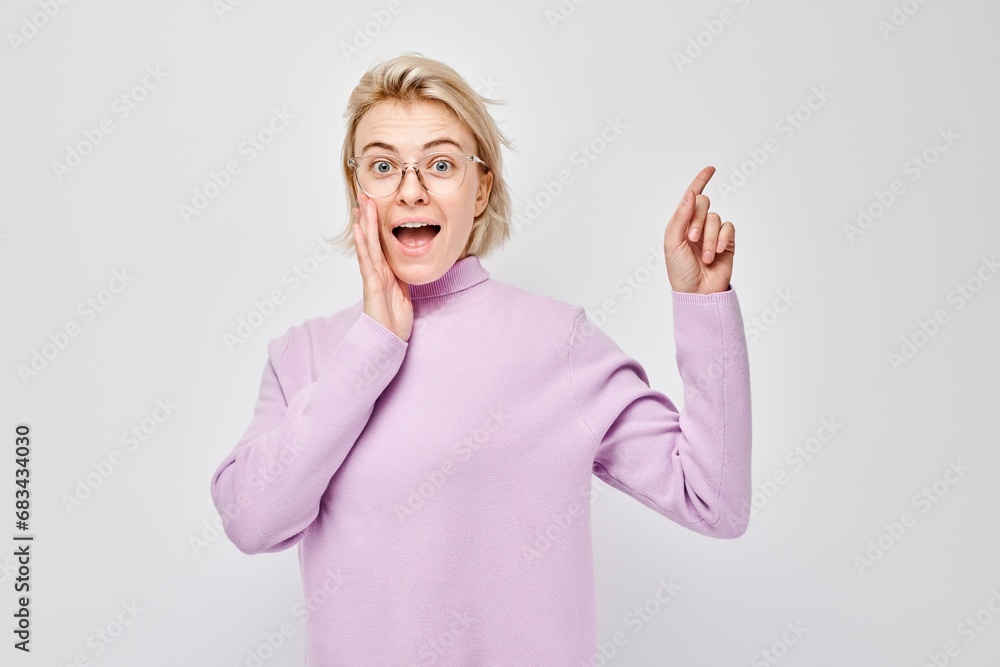 Young blond woman in casual pointing aside finger, demonstrating empty space for product or text isolated on white studio background. Young blond woman in casual pointing aside finger, demonstrating empty space for product or text isolated on white studio background.