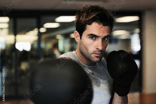 Man, boxing gloves and punch with gym for fitness, wellness or training for fight, performance or sport. MMA, boxer or strong for contest, competition or exercise for development, sweat and workout © A.B./peopleimages.com