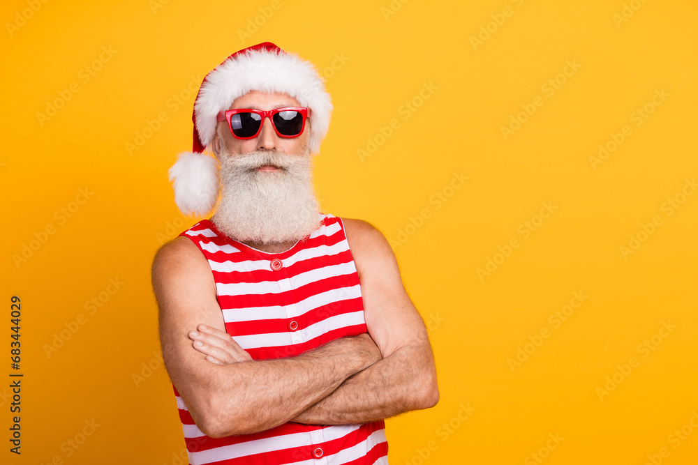 Photo of confident serious senior guy dressed christmas swimwear hat glasses arms crossed empty space isolated yellow color background