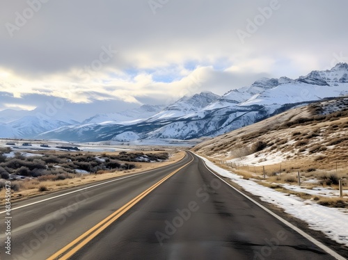 a narrow roadway going towards mountains covered with snow in in winters