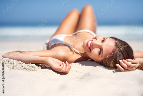 Woman, portrait and sunbathing on beach sand or vacation for nature water, sea rest or holiday travel location. Female person, bikini and tanning outdoor sunshine, tourism journey at blue sky coast
