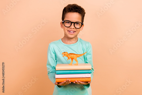 Photo of clever cute boy nerd wear stylish outfit hands hold book learning history ancient animals isolated on beige color background