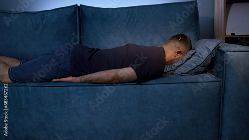 Tired boy slumping on couch feeling listless. Media. Feeling depressed, lack of motivation, sadness, boredom. Exhausted, he collapses on the couch from stress. photo