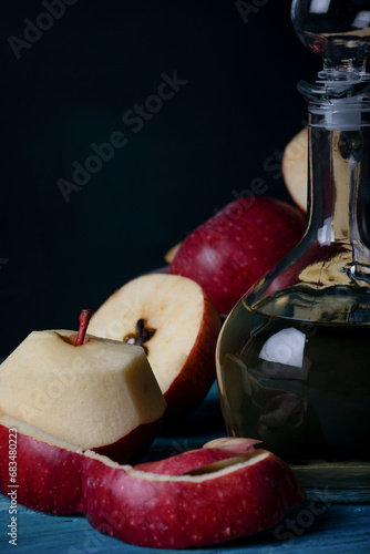 Fresh apples and apple vinegar in bootle on blue wooden background