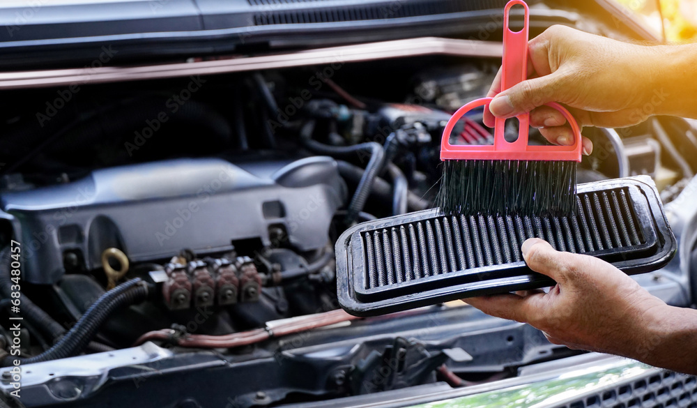 Obraz premium Hands man auto mechanic holding brush to clean dirty car air filters, cleaning process on car engine background for maintenance or repair service concept.