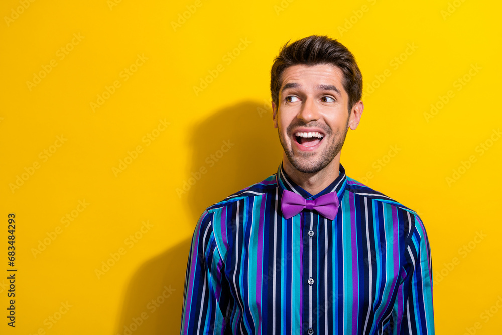Obraz premium Portrait of ecstatic guy dressed stylish shirt bow tie staring at discount empty space isolated on vibrant yellow color background