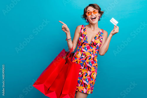 Photo of funny woman dressed colorful clothes hold outfit look directing empty space credit card in hand isolated on blue color background
