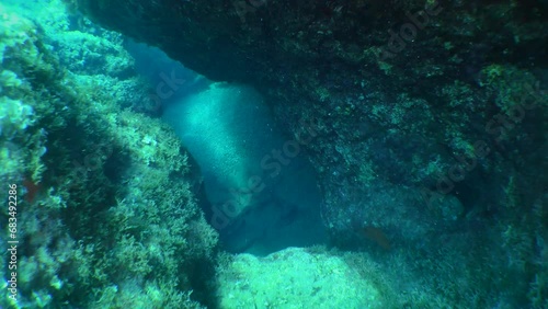 Snorkeling, diving: the camera penetrates through a hole into a stone grotto. photo