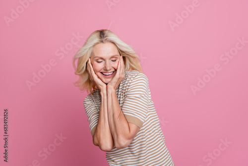 Photo of positive retired lady enjoy touch face after wrinkles peeling procedure isolated on pink color background