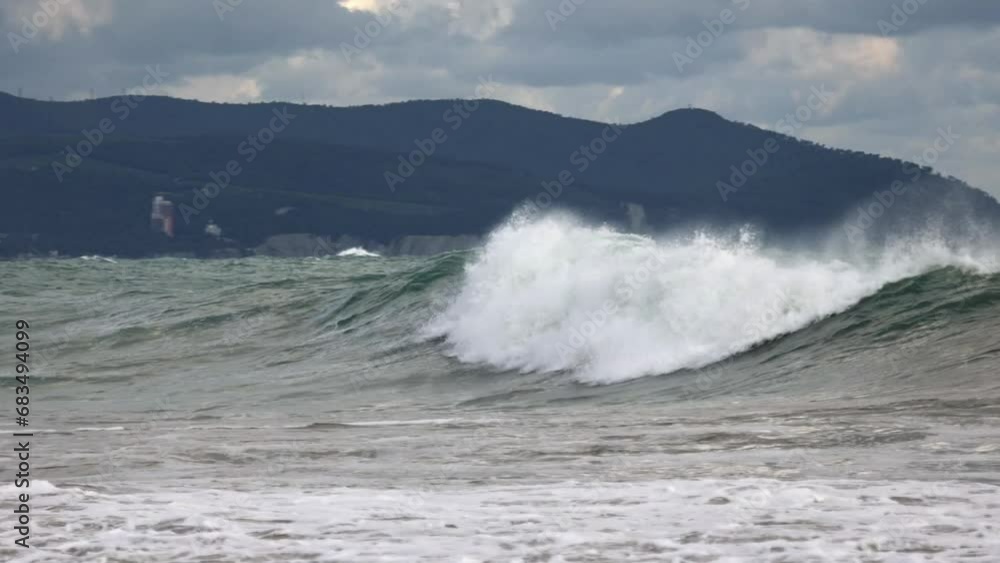 Winter storm in the resort of Gelendzhik. Large storm waves on the background of the lighthouse. Sea foam. High cliffs in the background. Winter storm in the resort of Gelendzhik. Large storm waves on the background of the lighthouse. Sea foam. High cliffs in the background.