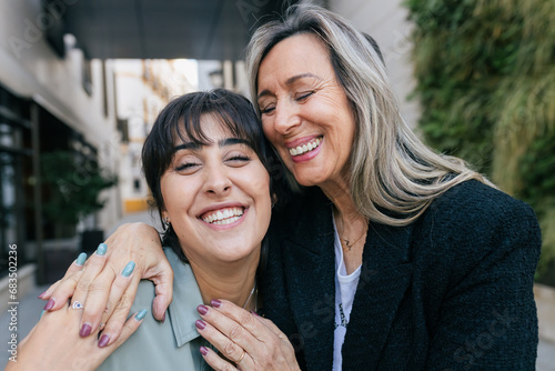 Smiling mature woman hugging friend from behind in city photo