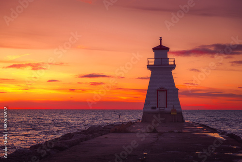 Lighthouse at sunset overlooking a lake.