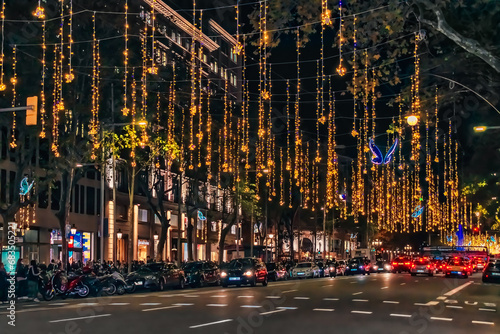 Barcelona, Spain - November 26, 2021: Christmas in Barcelona. Festive gold garlands with blue butterflies hang and sparkle on the road on Paseo de Gracia street at night. City illumination