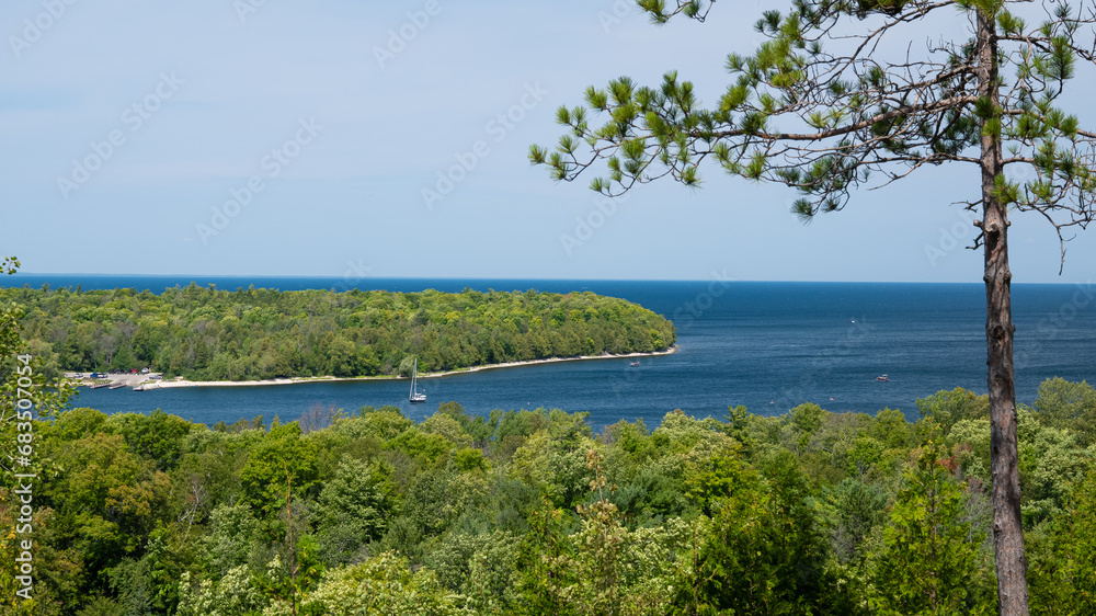 Scenic overlook view of the Green Bay of Lake Michigan in Door County, Wisconsin, with green vegetation, a cove with boats, and the blue water and sky.