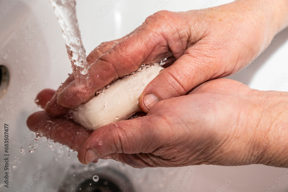 Fototapeta premium An elderly man washes his hands with soap, wrinkles, old.