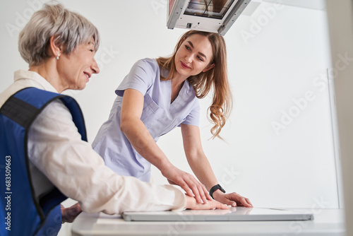 Smiling woman making arm examination using x-ray machine photo