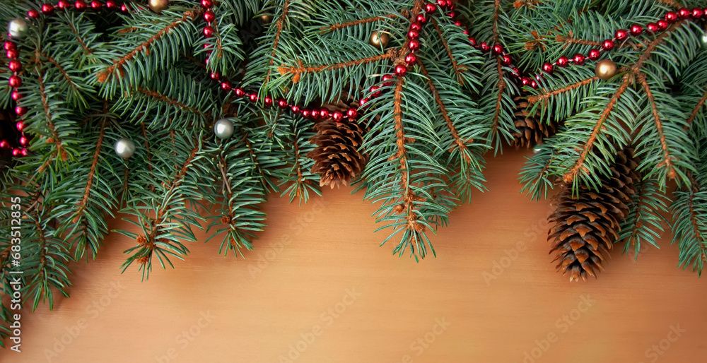 Christmas tree branches, cones and pink beads on a wooden texture Christmas tree branches, cones and pink beads on a wooden texture